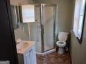 Bathroom featuring a stand-up shower, toilet, vanity with sink, mirror, and brown tile floor at 5549 Highway 42, Ellenwood, GA 30294