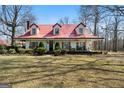 Charming two-story home featuring a red metal roof, dormer windows, and a spacious front yard at 680 Milligan Creek Rd, Roopville, GA 30170