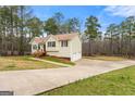 Spacious home featuring a long driveway and an attached two-car garage surrounded by mature trees at 370 Burton Dr, Douglasville, GA 30134