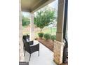 Welcoming covered porch featuring brick columns, stylish seating, and a view of the landscaped front yard at 5745 Pickens Garden Ln, Powder Springs, GA 30127