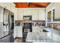 Well-appointed kitchen featuring white cabinets, modern appliances, and eye-catching brick backsplash at 509 Eskew Rd, Mcdonough, GA 30252