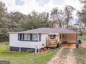 Charming home with covered carport, landscaping and a 'Welcome' sign near the front porch at 1202 Coan Dr, Locust Grove, GA 30248