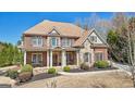 Attractive two-story brick residence featuring stone accents, a cozy front porch, and lush landscaping at 3149 Hidden Falls Ne Dr, Buford, GA 30519