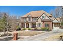 Beautiful two-story brick home showcasing a charming porch, stone accents, and a beautifully landscaped front yard at 3149 Hidden Falls Ne Dr, Buford, GA 30519