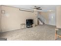 Bright living room with neutral carpet, ceiling fan, stairs leading to a second floor, and entry door at 71 Russell Rd, Mcdonough, GA 30252