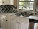 Bright kitchen with a stainless steel sink, modern fixtures, and sleek backsplash under a window at 1271 Sanders Dr, Lake City, GA 30260