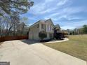 View of home exterior featuring a three-car garage and mature trees at 125 Mcintosh Estates Dr, Sharpsburg, GA 30277