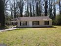 A ranch-style house with a covered porch area and a spacious front lawn surrounded by trees at 61 Scoby Ct, Jonesboro, GA 30238