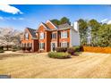 Beautiful two-story red brick home featuring meticulously landscaped grounds and lush trees at 265 Ridgewood Dr, Fayetteville, GA 30215