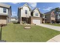 Beautiful two-story home showcasing a brick and siding exterior and large driveway with landscaping at 2458 Walker Dr, Hampton, GA 30228