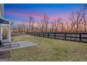 Spacious backyard featuring a well-maintained lawn, a patio, and a black fence bordering a wooded area at 8110 Brewton Bnd, Cumming, GA 30028