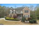 Traditional brick home with dormer windows, shutters, a front porch, and lush landscaping at 308 Tussahaw Trl, Locust Grove, GA 30248