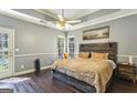 Serene main bedroom featuring a wooden accent wall, tray ceiling, and natural light at 5163 Holly Springs Dr, Douglasville, GA 30135