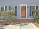 Close-up of the front door with decorative wreath, flanked by windows with black shutters and brick steps at 233 Creekstone Bnd, Peachtree City, GA 30269