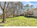 This backyard showcases a spacious lawn, mature trees, and a wooden deck at 104 Amberidge Nw Dr, Cartersville, GA 30121