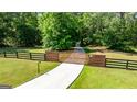 Private gated entrance with black fencing and a smooth concrete drive, surrounded by mature trees and green lawn at 129 Old Norton Rd, Fayetteville, GA 30215