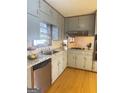Well-lit kitchen features wood floors, granite countertops, gray cabinets, and stainless steel dishwasher at 2574 Rosedale Dr, Morrow, GA 30260