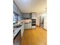 Well-lit kitchen features wood floors, granite countertops, gray cabinets, and stainless steel dishwasher at 2574 Rosedale Dr, Morrow, GA 30260