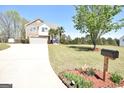 Spacious front yard with manicured lawn and driveway leading to a two-story home with stone and siding exterior at 116 Ducati Dr, Mcdonough, GA 30252