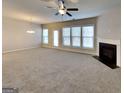 Spacious living room boasts neutral carpet, abundant natural light, ceiling fan, and a cozy fireplace, perfect for relaxation at 3713 Upland Dr, Mcdonough, GA 30253