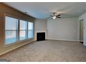Bright living room featuring neutral carpet, a ceiling fan, a fireplace, and large windows providing ample natural light at 3713 Upland Dr, Mcdonough, GA 30253