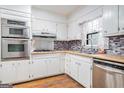 Well-lit kitchen with stainless steel appliances, white cabinets, and a colorful backsplash at 4230 Iris Brooke Ln, Snellville, GA 30039