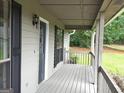 View of the covered front porch with wood railings and a front door with window, and decorative sconce at 130 Bradley Pl, Mcdonough, GA 30253