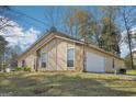Home exterior with a white garage door and stone accents and manicured lawn at 3396 Framingham Dr, Lithonia, GA 30038