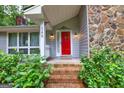 Inviting entrance with a bright red door, decorative porch lights, and a cozy welcome mat, surrounded by greenery at 346 Buckingham Sw Dr, Conyers, GA 30094