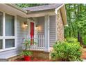 Close-up of the entryway with its red door, white picket fence, and brick base, framed by lush greenery at 346 Buckingham Sw Dr, Conyers, GA 30094