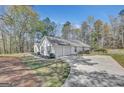 This property features a three-car garage and a long driveway with a serene, wooded backdrop at 147 Kripple Kreek Dr, Sharpsburg, GA 30277