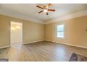 Bright living room with light wood-look flooring, a ceiling fan, and access to other rooms at 34 Ivy St, Porterdale, GA 30014