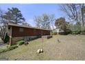Exterior view of home's back and yard with mature trees and a small patio area; some equipment in view at 5217 Hollyhock Rd, Douglasville, GA 30135