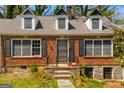 Close-up of the brick home's facade, highlighting the arched entryway, black shutters, and three dormer windows at 2255 Beecher Sw Rd, Atlanta, GA 30311