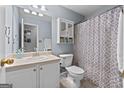 Bright bathroom features a vanity, toilet, and a shower/tub combo with a patterned curtain at 1022 Miss Amber Way, Locust Grove, GA 30248