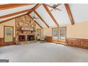 A cozy living room features a striking stone fireplace, wood beams, and large windows offering natural light at 426 Old Senoia Rd, Fayetteville, GA 30215