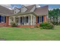 Inviting brick porch with white columns and charming details on a well-maintained lawn at 557 Arrowhead Cir, Rutledge, GA 30663
