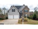 Attractive two-story home with stone and siding exterior, attached garage, and well-maintained front lawn at 347 Cobblestone Ct, Hampton, GA 30228