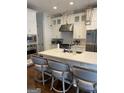 Well-appointed kitchen featuring a large island with seating and stainless steel appliances with white cabinets and backsplash at 813 Creekgarden Court, Atlanta, GA 30339