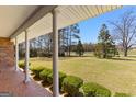 Expansive front yard view from covered porch featuring mature trees and manicured boxwoods at 275 S Bethany Rd, Mcdonough, GA 30252