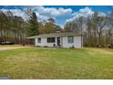 Charming home featuring white brick, black trim, lovely lawn, and covered parking at 1910 Reese Rd, Rutledge, GA 30663
