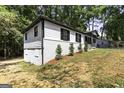 Side view of a home showcasing its white siding, brick foundation, and tree-lined surroundings at 2145 Venesa Cir, Austell, GA 30168
