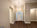 Inviting entryway featuring modern wood flooring, a decorative chandelier, and a bright entry door at 596 Carlton Rd, Palmetto, GA 30268