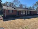 Charming brick home featuring well-maintained lawn and a covered front porch with classic design elements at 2533 Whispering Pines Dr, Grayson, GA 30017