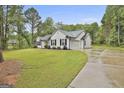 Exterior view of home with long driveway leading to the side-entry garage, lush lawn, and mature trees at 2112 Highway 54, Moreland, GA 30259
