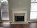 Bright living room featuring a fireplace with granite surround, two windows with blinds, and hardwood floors at 40 Canterbury Dr, Grantville, GA 30220