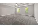 Spacious main bedroom features plush carpet, natural light, and a tray ceiling with fan at 60 Charlotte Blvd, Stockbridge, GA 30281