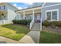 Inviting exterior view with a covered front porch, steps, manicured lawn and red door at 5124 N Pratt St, Covington, GA 30014