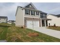 Two-story home with a two-car garage, a mix of siding and brick, and a young tree in the front yard at 161 Aster Ave, Locust Grove, GA 30248
