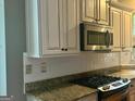 Kitchen featuring stainless steel microwave above a matching oven, granite countertop, and ample cabinet space at 9340 Basswood Way, Jonesboro, GA 30236